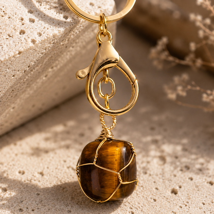 Porte-clés Œil de Tigre naturel Gold en macro sur travertin, détail de la pierre et du métal